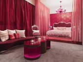 Red, Neo-Baroque bedroom with modern side tables in front of bed on platform and closed curtains