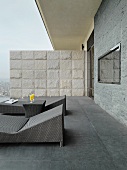Modern outdoor loungers on roof terrace in various shades of grey with stone partition