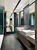 Washstand and base cabinet in spacious bathroom with dark-grey tiles on floor and walls