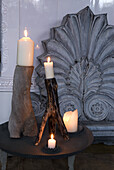 Candles on rustic wooden holders in front of an antique wall relief