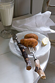 Rustic table setting with potatoes on a white plate, old wooden forks and milk in a glass