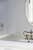 Waschbecken mit Vintage Wasserhahn, darüber ovaler Spiegel