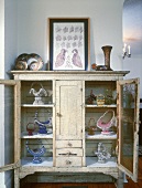 Vintage display cabinet with collection of baskets and framed picture of birds