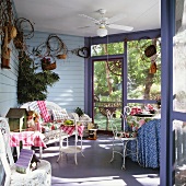 Verglaste Veranda mit Korbmöbeln und einem Deckenventilator; gemusterte Textilien sorgen für ein heiteres Ambiente
