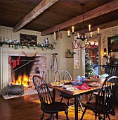 A dining room decorated for Christmas with a fire burning in the grate and a view of the Christmas tree