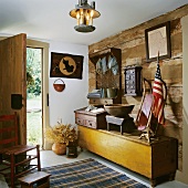 Diele mit einer rustikalen Holzwand im Blockhausstil mit einer langen Holztruhe und Antiquitäten aus der amerikanischen Gründerzeit