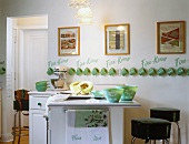 Vintage-style kitchen with counter, bar stools and collection of Fire King mugs hanging on wall
