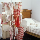 Antique bed behind red and white vintage bed linen hanging on a clothes horse