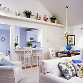Offener Wohnraum mit weissen Polstermöbeln und einer Küchentheke als Verbindung zur Küche