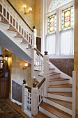 Grand staircase with ornate stained and leaded glass windows and carved wood panelling on walls