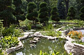 Gartenanlage mit Teich und geschnittenen Bäumen