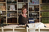 Fabric shop - woman standing in front of pattern books on shelves and sample books on counter