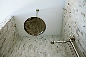 Kopf- und Handbrause im Retrostil in gemauerter Dusche mit grau geflammten Marmorfliesen
