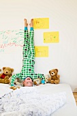 Boy doing headstand on bed