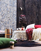 Häkeldecke und Wolldecken auf einem Bett vor Paneelen in Steinwand- und Holz-Optik