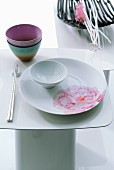 Japanisches Tischgedeck auf weißem Beistelltisch im Hintergrund Dekoschale mit Ästen und Blütenzweig