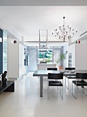 Grauer Esstisch und schwarze Stühle unter Designer Hängelampe in offenem minimalistischen Wohnraum