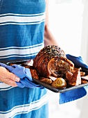 A woman serving glazed roast pork with roast pears