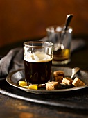 Shot Glass of Espresso with Brown Sugar Cubes and a Thin Lemon Peel; On a Metal Tray; Empty Glass