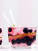 A cocktail made with gin, tonic water, blueberries and lime
