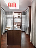 Großräumiger Ankleideraum mit transparenten Vorhängen und einer Schmuckvitrine in der Mitte des Raums