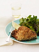 Crispy Fried Fish Fillet with a Green Salad; On a Plate with a Fork