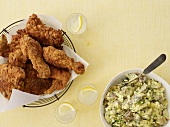 Fried Chicken in a Wire Basket; Bowl of Potato Salad; From Above