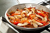 Chicken and Peppers Cooking in a Skillet