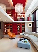 Nach oben offener Wohnraum mit Polstercouch und Blick auf Galerie und Kronleuchter an roter Decke