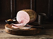 Cooked ham, partly sliced, on chopping board