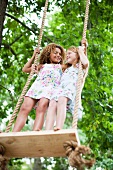 Smiling girls standing on tree swing
