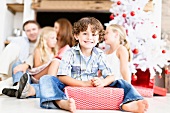 Boy sitting with wrapped Christmas gift