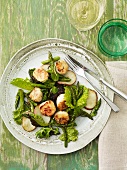 Scallops with Greens and Sliced Potatoes on a Plate; Fork and Knife