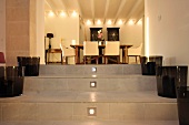 Dunkelgraue Glasbehälter auf gefliesten Stufen mit eingelassener Beleuchtung und Blick durch breiten Durchgang in Esszimmer