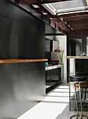 Bar stools at kitchen counter and black sliding wall in front of designer kitchen