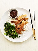 Breaded and Baked Chicken Sliced Over Rice with Dipping Sauce and Wilted Greens