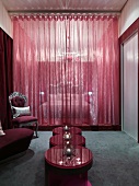 Vorraum mit Beistelltischset auf grauem Teppich und neobarockem Stuhl vor rotem transparentem Vorhang