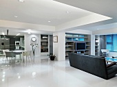 Moderner Wohn- und Essraum mit grauem Sofa auf glänzendem weissen Boden