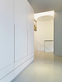 Weisser Garderobenschrank in modernem Vorraum und Blick auf Treppenabgang