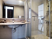 Vanity with stone tiles in front a a mirror next to a glass shower stall