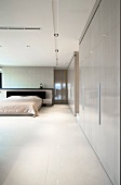 Minimalist bedroom with built-in cupboards and illuminated, suspended ceiling panels