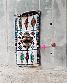 Rag rug made from old clothes hanging on concrete wall
