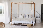 Romantic crocheted throw and capiz shell discs hanging from frame of four-poster, vintage bed
