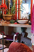 Wash basin, house plants and bottles of cosmetics on concrete counter in bathroom