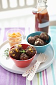 Two Small Bowls of Assorted Meatballs on a Tray with Plastic Forks