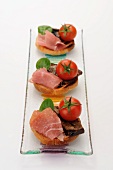 Toast topped with marinated aubergines, raw ham and tomatoes