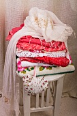 Stack of clothes, scarf and fabric heart on wooden stool