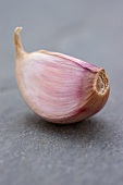 A garlic clove on a slate surface (close-up)