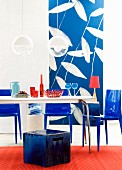 Wohnraum in Blau- & Rottönen mit Esstisch, Hocker, Plasikstühlen & Fototapete