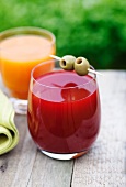 A glass of carrot and orange juice and a glass of beetroot and apple juice
